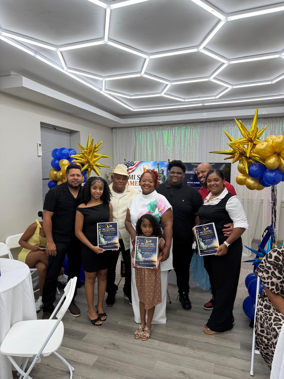 Familia posando con Ingrid Morales y sus libros frente a la decoración de la inauguración.